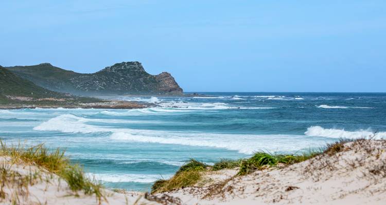 Golven die beuken op een strand met rotsachtige kustlijn.