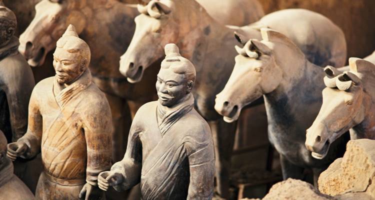 Terracotta figures of soldiers and horses from an archaeological exhibit.