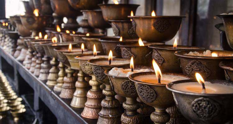 Reihe von Öllampen, die in verzierten Metallhaltern brennen.