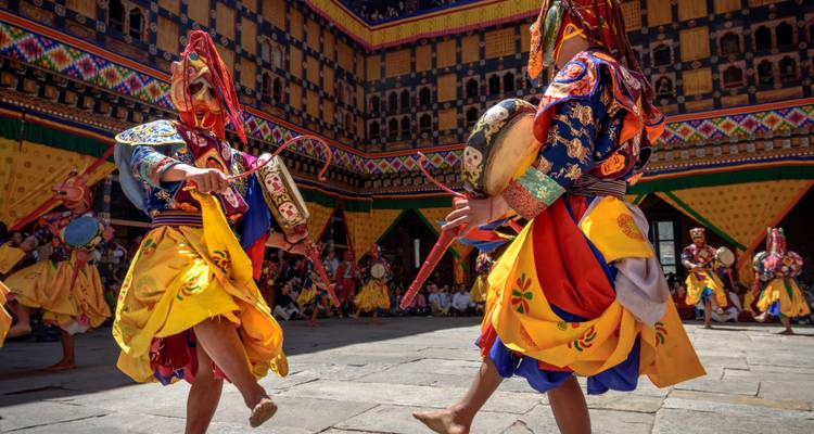Bunte maskierte Tänzer führen einen traditionellen Tanz in einem Innenhof auf.