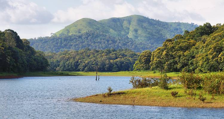 Serene lake with forested hills inside Periyar National Park.