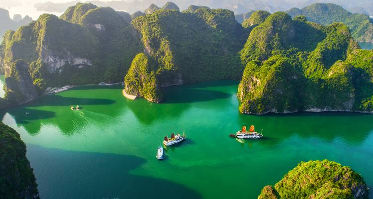 Karsts de piedra caliza rodeados de aguas verdes y botes en la Bahía de Halong.