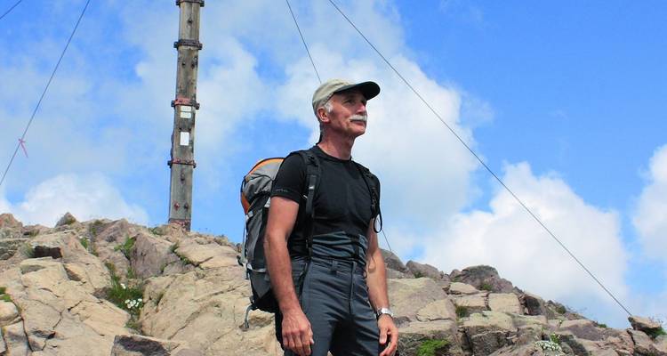 Man standing on rocky terrain with blue sky.