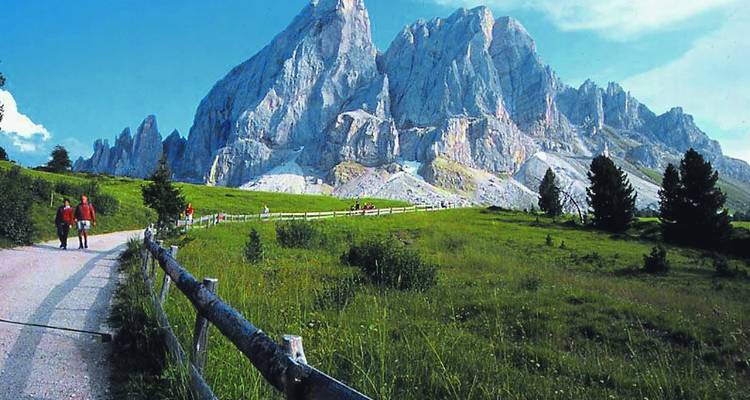 Mountain path with hikers and rugged peaks.