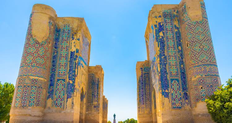 Massive Überreste von zwei hoch aufragenden, mit Mosaiken bedeckten Mauern eines antiken Tores mit strahlend blauem Himmel darüber.