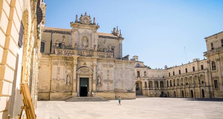 La façade ornée de la cathédrale de Lecce domine une piazza ensoleillée de pierre dorée avec peu de visiteurs.