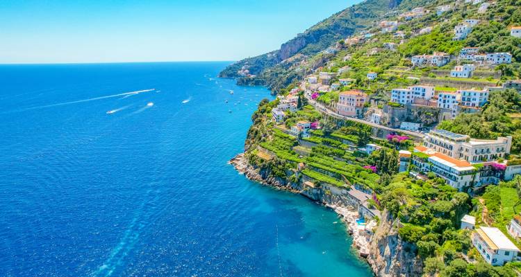 Lebendige Klippendörfer und terrassenförmige Gärten überblicken die tiefblauen Gewässer der Amalfiküste an einem klaren Sommertag.