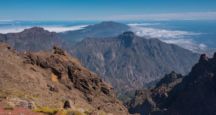 Vue panoramique plongeante sur l'accidentée Caldera de Taburiente avec ses couches de sommets et une mer de nuages en contrebas.