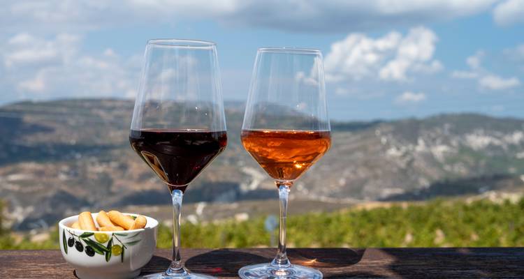 Zwei Gläser Wein mit einer malerischen Bergkulisse.