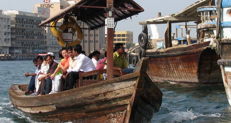 People on a traditional wooden boat in a city canal.