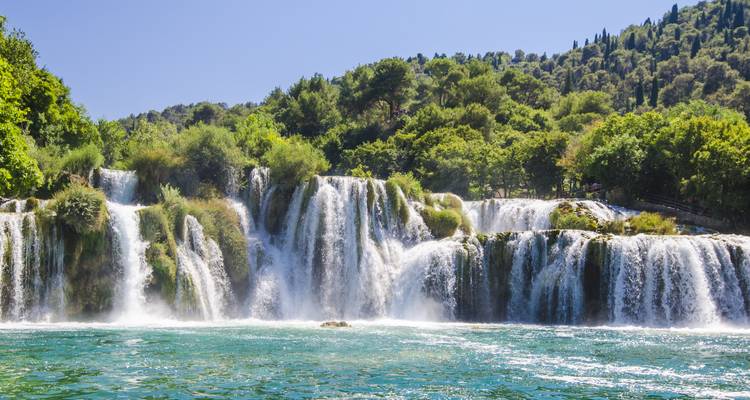 Wide cascade of Skradinski Buk waterfalls plunging into emerald water surrounded by lush greenery