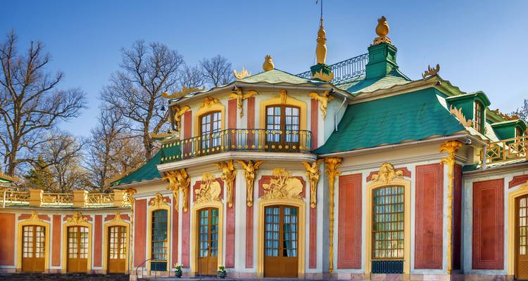 Bunter Barock-Pavillon mit grünem Dach und goldenem Dekor vor klarem blauen Himmel.