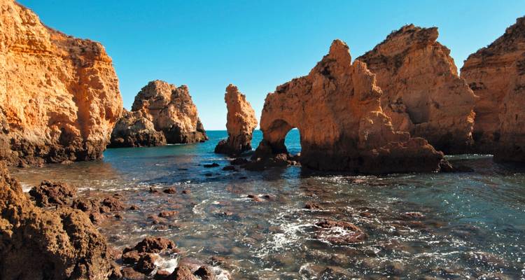 Hermosa costa escarpada con formaciones rocosas y agua cristalina.