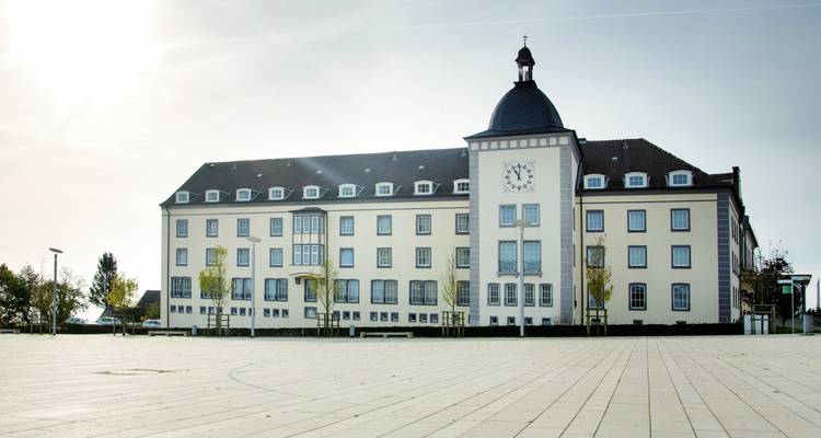 Großes Gebäude mit einem Uhrenturm auf einem leeren Platz.