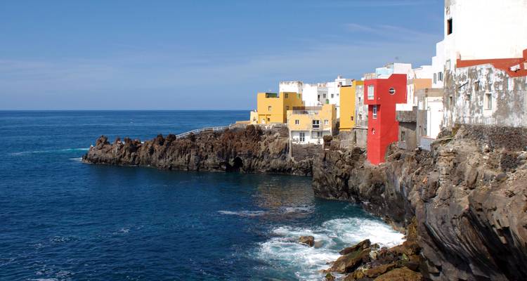 Cluster of colorful cliff-side houses above deep blue Atlantic waters on a clear day