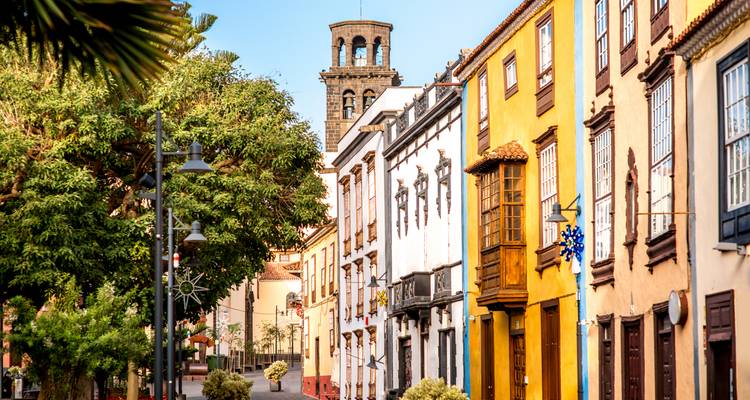 Charming pedestrian street lined with colorful colonial buildings and a distant bell tower on Tenerife