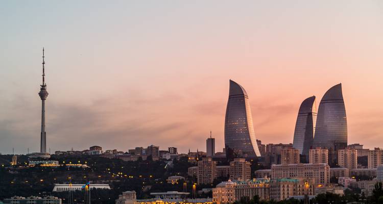 Nächtliche Skyline von Baku mit den beleuchteten Flame Towers und dem Fernsehturm über der Stadtsilhouette.