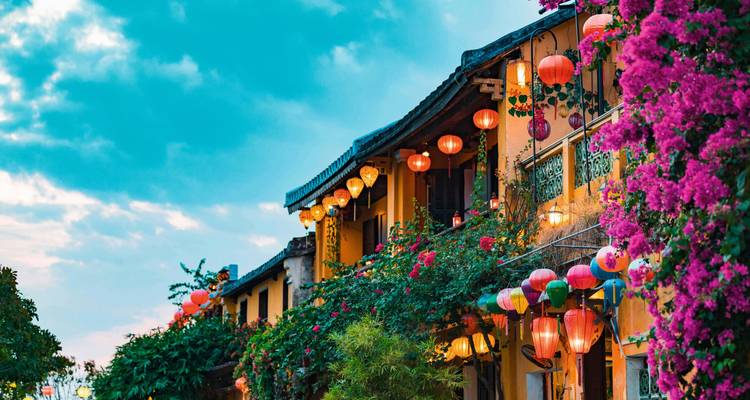Une rue décorée de lanternes et de fleurs au crépuscule.