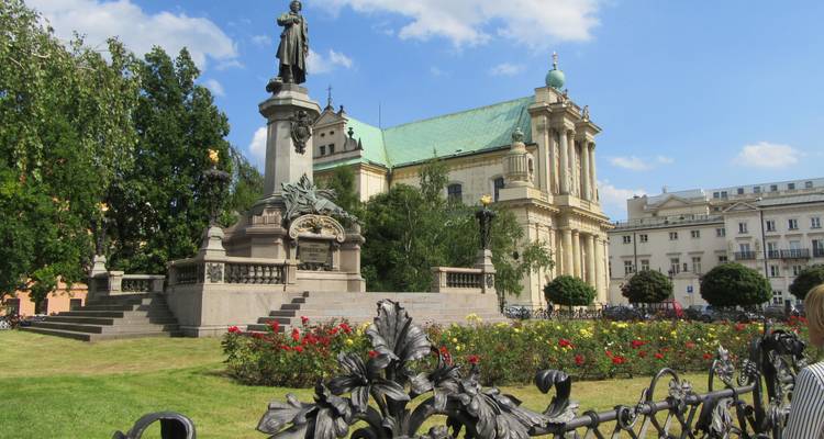 A statue in a garden with a historic church in the background.
