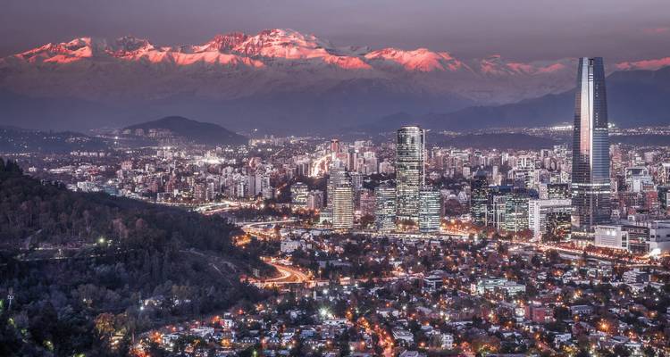 Paysage urbain crépusculaire de Santiago avec les Andes enneigées brillant de rose derrière les gratte-ciel.