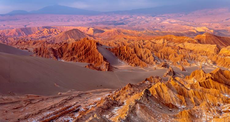 Vue aérienne panoramique de crêtes rouges semblables à Mars et de dunes de sable dans le désert d'Atacama au Chili au crépuscule.