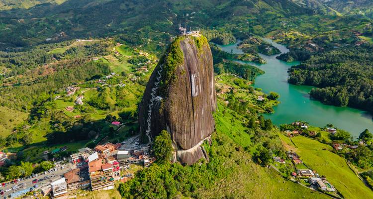 Luchtfoto van de massieve granieten monoliet Piedra del Peñol die oprijst boven het groene landschap en turquoise meren.