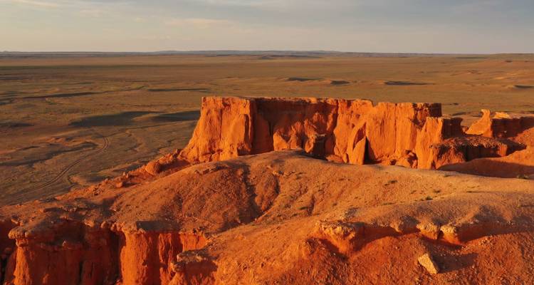Goldene Klippen von Bayanzag leuchten im späten Nachmittagslicht über der weiten mongolischen Wüstenebene