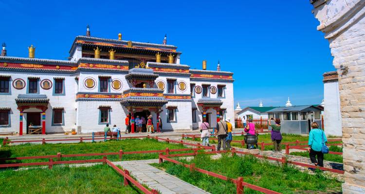 Besucher erkunden das weißwandige, golddachige Erdene Zuu Kloster an einem hellen Tag