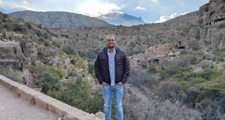 Persoon staand in een bergachtig gebied met stenen gebouwen.