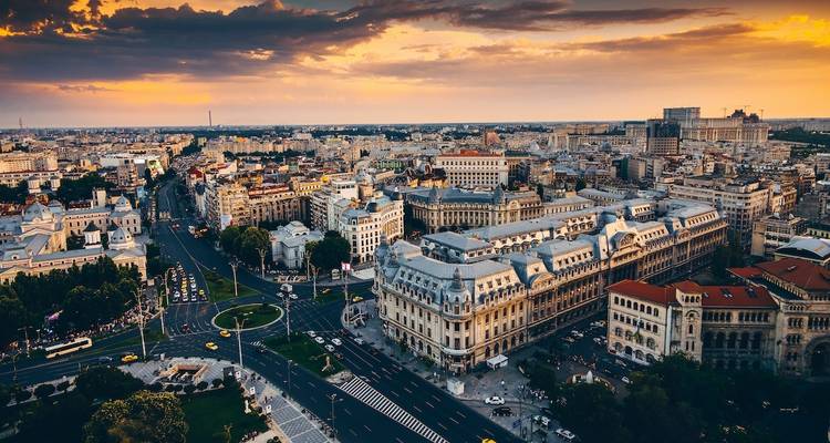 Cityscape view of a wide avenue and historic buildings at sunset.