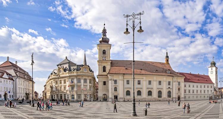 Sibiu main square with historic buildings and small crowds.