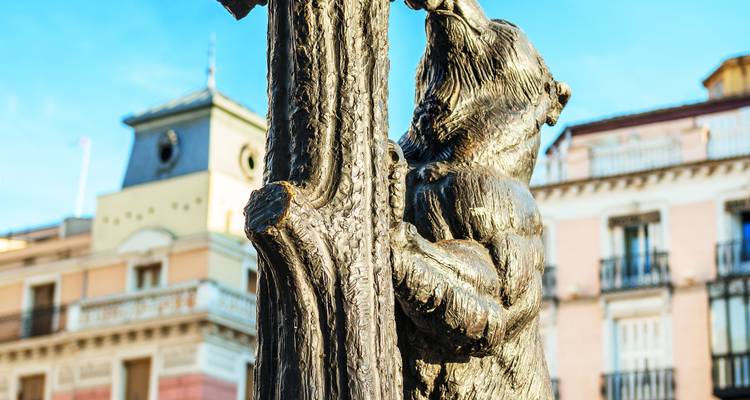 Statue eines Bären, der einen Baum in städtischer Umgebung erklimmt.