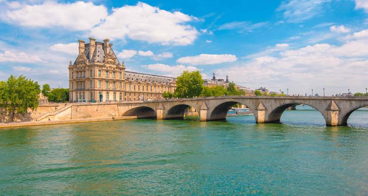 Un pont historique traversant la Seine avec un grand bâtiment en arrière-plan.
