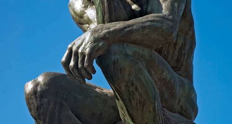 Gros plan d'une main sculpturale célèbre positionnée en contemplation contre un ciel dégagé.