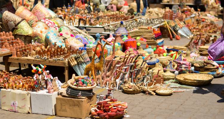 Kleurrijke straatmarktkraam die overloopt met geweven manden, aardewerk, houten kamelen en heldere handwerk gerangschikt op kisten en tafels.