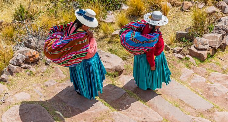 Twee vrouwen in traditionele Zuid-Amerikaanse klederdracht lopen op een pad.