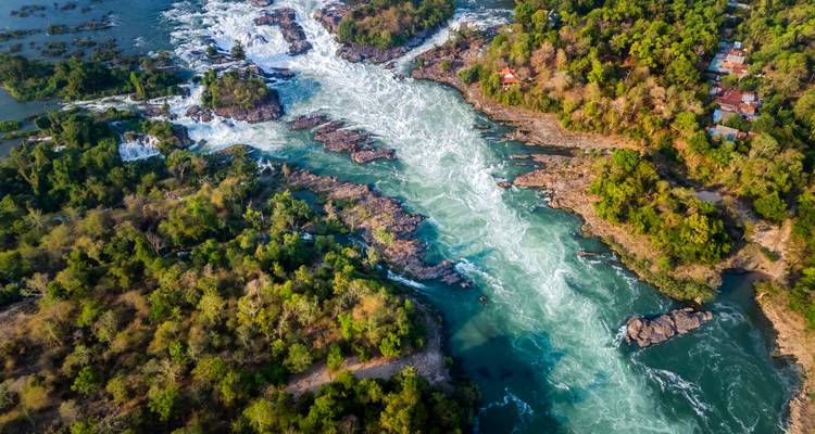 Luftaufnahme von mächtigen Wasserfällen und Stromschnellen, die sich durch üppig grüne Inseln im Mekong-Fluss schlängeln.