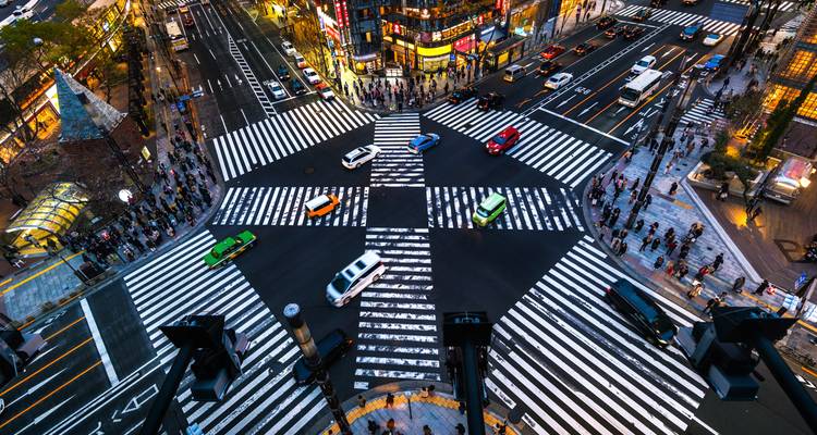 Vista aérea nocturna de un cruce peatonal multidireccional muy transitado en una ciudad iluminada con neón