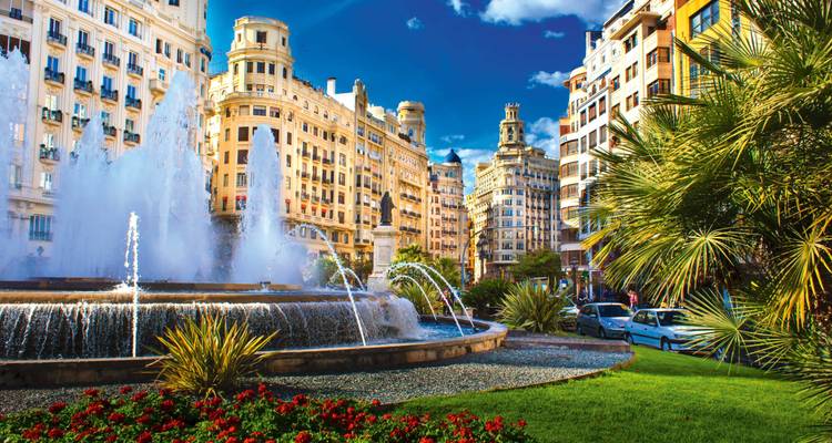 Paysage urbain vibrant avec fontaines et architecture historique sous un ciel bleu.