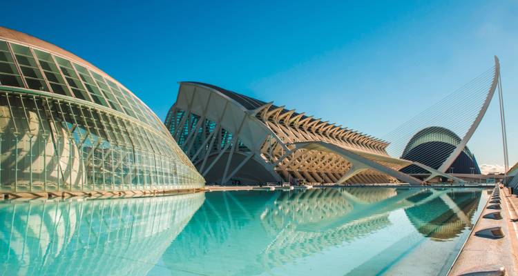 Complexe architectural moderne avec structures de verre et reflets dans un bassin.