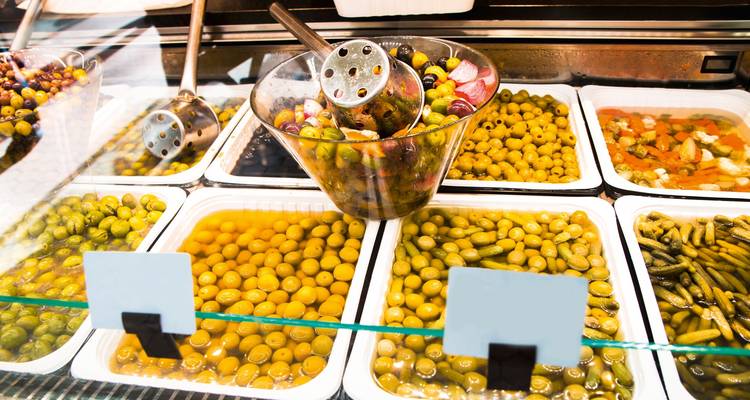 Variété d'olives marinées et de cornichons exposés dans un marché.