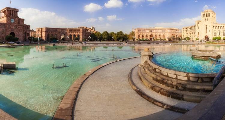 City square with historic buildings and a fountain.