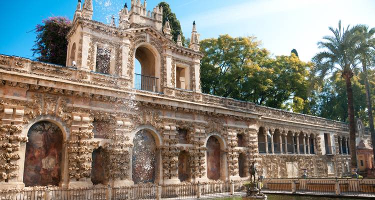 Elegante Fassade der Gärten des Realen Alcázar mit kaskadierenden Wassertropfen des Brunnens, die in der Sonne funkeln.