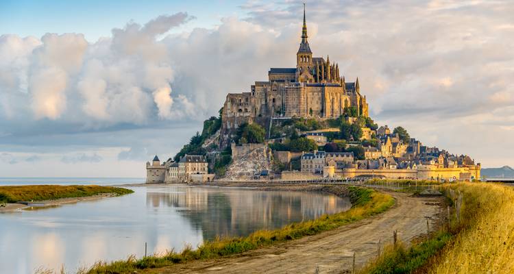 Iconic Mont Saint-Michel abbey rising above tidal flats at golden sunrise