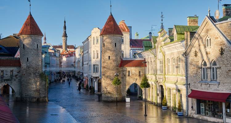 Mittelalterliche steinerne Tortürme, die eine Fußgängerstraße in Tallinns Altstadt nach Regenschauern flankieren.