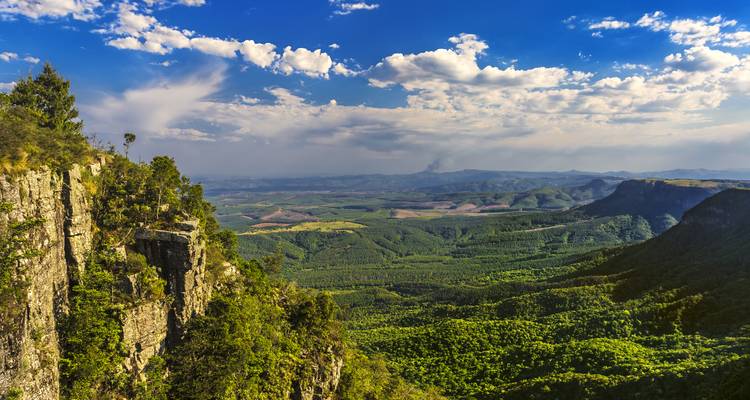 Panoramic view of a vast valley with lush greenery and clouds.