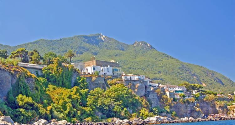 Weelderige groene klif bezaaid met villa's onder beboste toppen op het eiland Ischia.