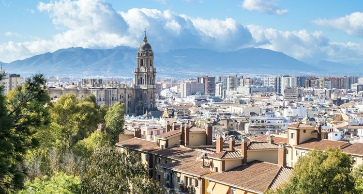 Stadtansicht mit einer Kathedrale und Bergen im Hintergrund.