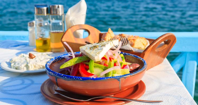 Salade grecque fraîche garnie de fromage feta servie sur une table en bord de mer sous un soleil éclatant.