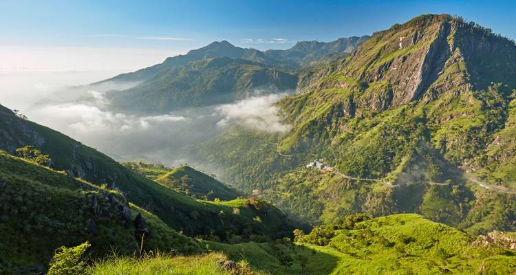 Dramáticas crestas montañosas y valles llenos de niebla cerca de Ella bajo un cielo matutino brillante
